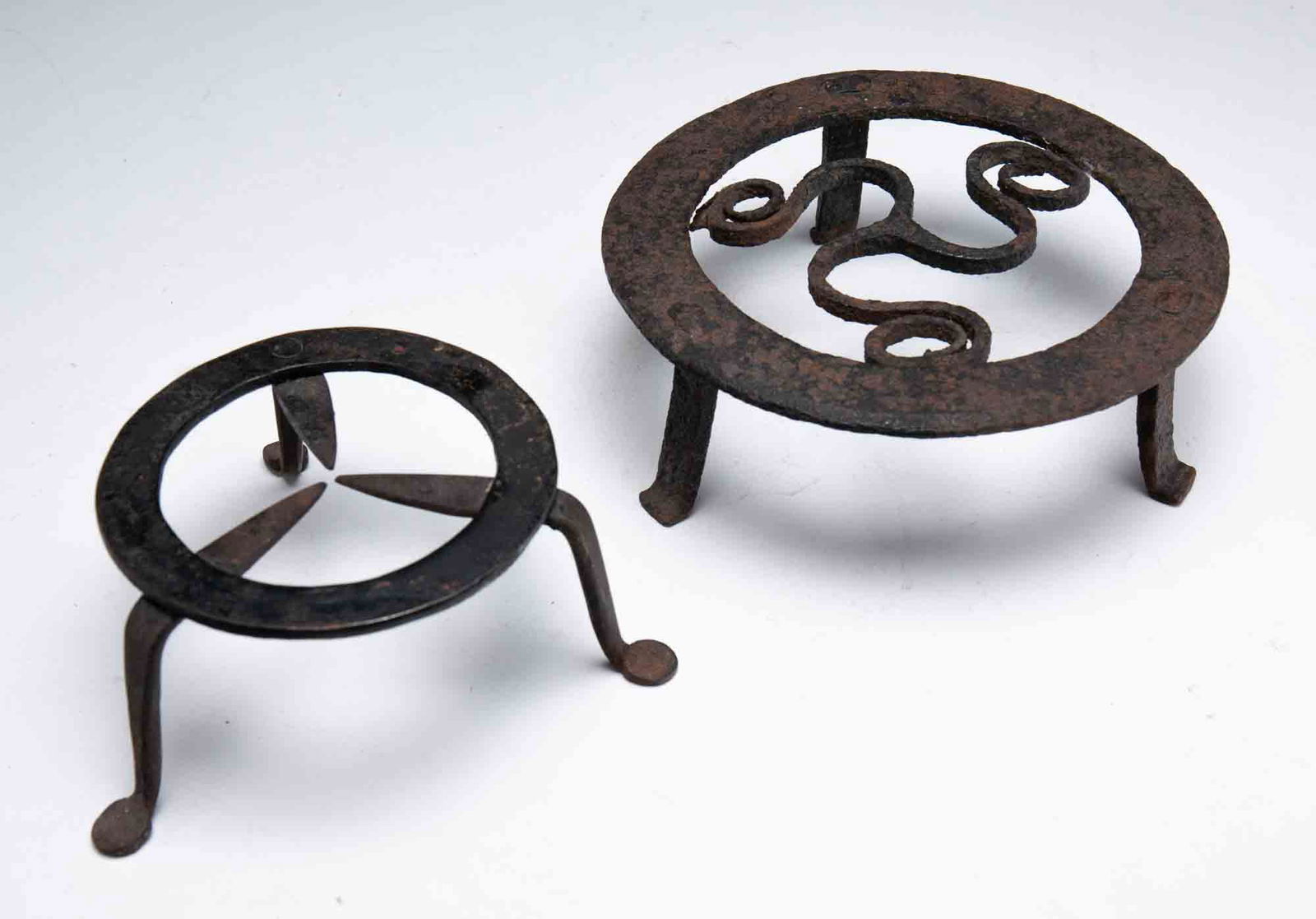 TWO FORGED IRON TRIVETS. (1 of 1)