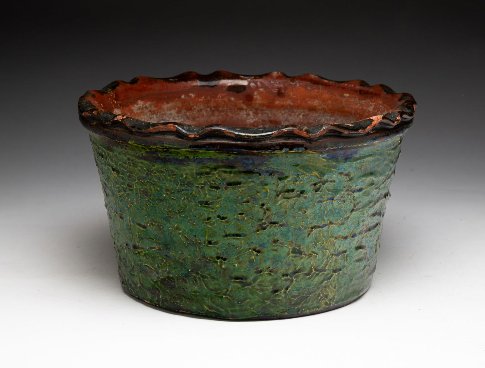 #NAME?: =REDWARE FLOWER POT WITH GREEN GLAZE. American, 19th Century. Possibly Bradford Pottery. Slightly tapered form with a textured body and glazed in green and black, the top with a pie crimp rim over a b