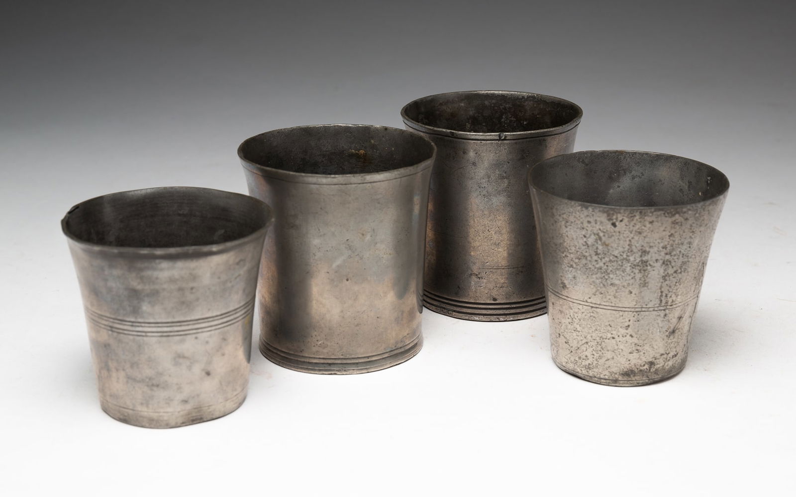 FOUR PEWTER TUMBLERS.: FOUR PEWTER TUMBLERS. English, 19th Century. One marked "Barron Strand". Nice patina. 2.75"h. to 3.25"h. From the collection of Carol Schulman (Chesterland, Ohio).
