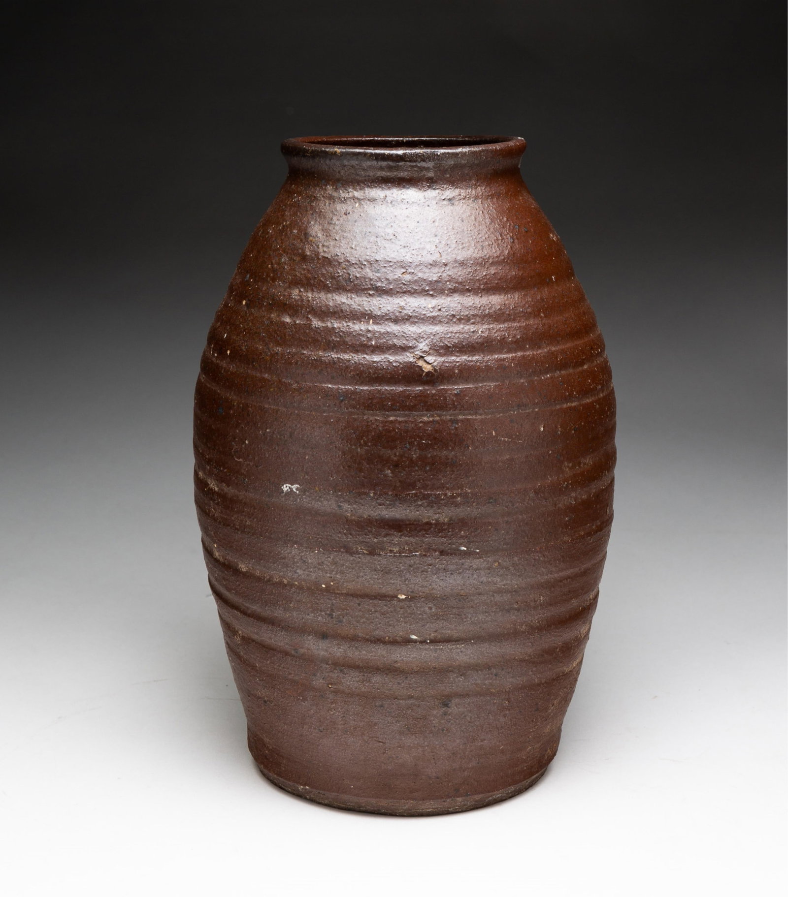 SOUTHERN STONEWARE STORAGE JAR.: American, 19th Century. Ovoid form with ribbed body in dark glaze. 11"h.From the collection of the late Neil Zuehlke, Heartland, Wisconsin.