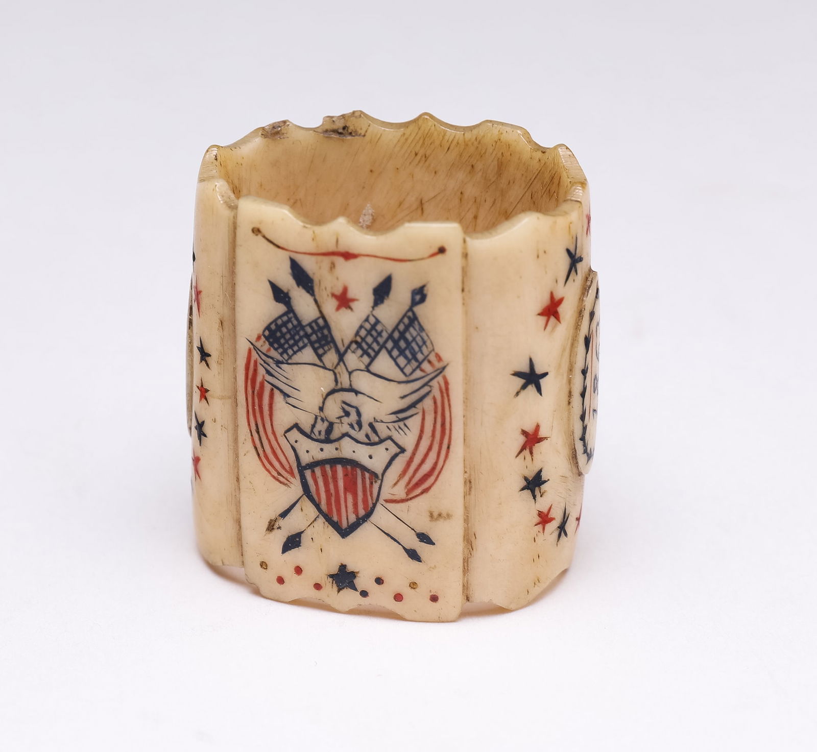 INCISED AND PAINTED BONE NECKERCHIEF SLIDE.: American, late 19th Century. Incised and painted blue and red with an eagle, shield, and American flags on one side; a military man on the other; inscribed 1863 and the initials H.B., with serrated ed