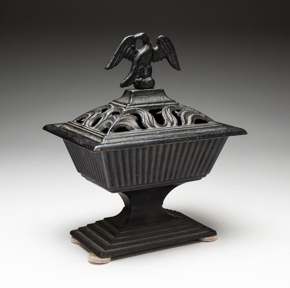 VICTORIAN CAST IRON CACHE POT.: American, second half 19th Century. Rectangular, canted sides with ribbing and stepped base. Reticulated lid with eagle finial. 9.5"h. 7.5"w. 5.5"d.
