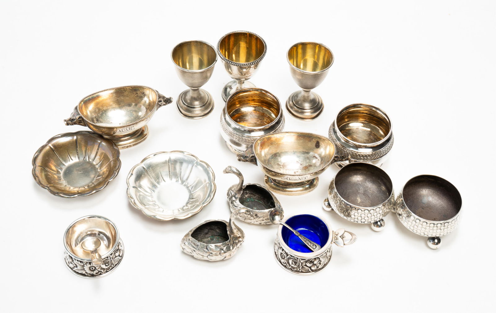 ASSORTED STERLING SILVER TABLE ACCESSORIES.: 19th and 20th Century. Comprising five pairs of sterling open salts; a pair of 800 silver open salts in the form of swans; three sterling egg cups; an enameled open salt with matching spoon; an additi