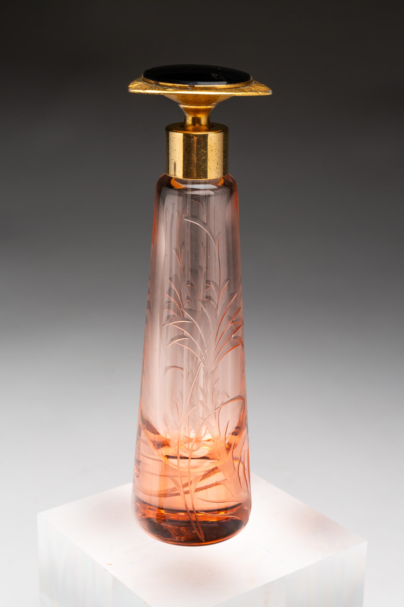 GLASS PERFUME BOTTLE WITH COMPLETE DAUBER.: American, circa 1920s. Pink glass with etched design and black inset in stopper. 5.75"h. From the lifetime collection of the late Cheryl Linville, Tipp City, Ohio.