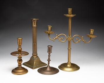 THREE BRASS CANDLESTICKS AND A CANDELABRA.