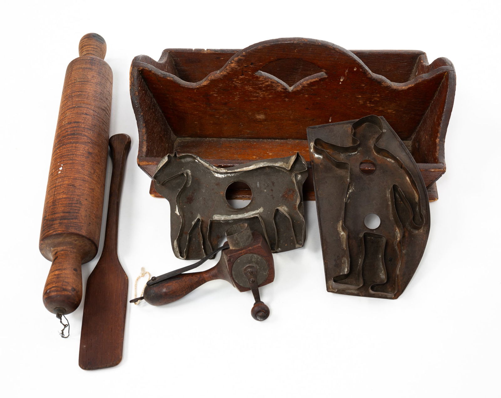 GROUP OF KITCHENWARE INCLUDING CUTLERY TRAY, TIGER MAPLE ROLLING PIN, NUTMEG GRATER, AND TIN COOKIE: American, 19th Century. Including a pine cutlery tray with canted sides and arched center with hand hold cut out, 14"w., a tiger maple rolling pin, 17"l., a thin spatula, nutmeg grater, and two cookie