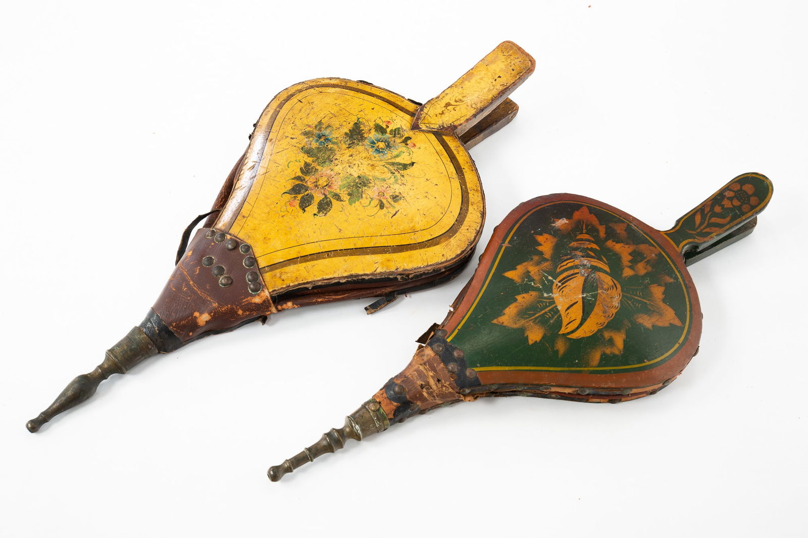 TWO PAINTED AND DECORATED TURTLE BACK BELLOWS.: American, 19th Century. Green with bronze powder stenciled shell and brass tack trim. 17.25"l. And cream colored with painted floral decoration. 18.75"l.
