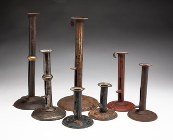 GROUP OF SEVEN TIN PUSH UP HOGSCRAPER CANDLESTICKS.