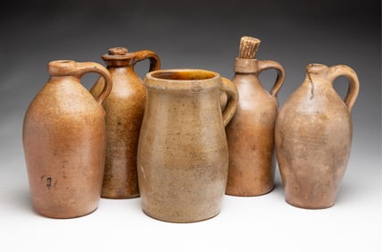 FIVE GLAZED STONEWARE SINGLE HANDLED JUGS.