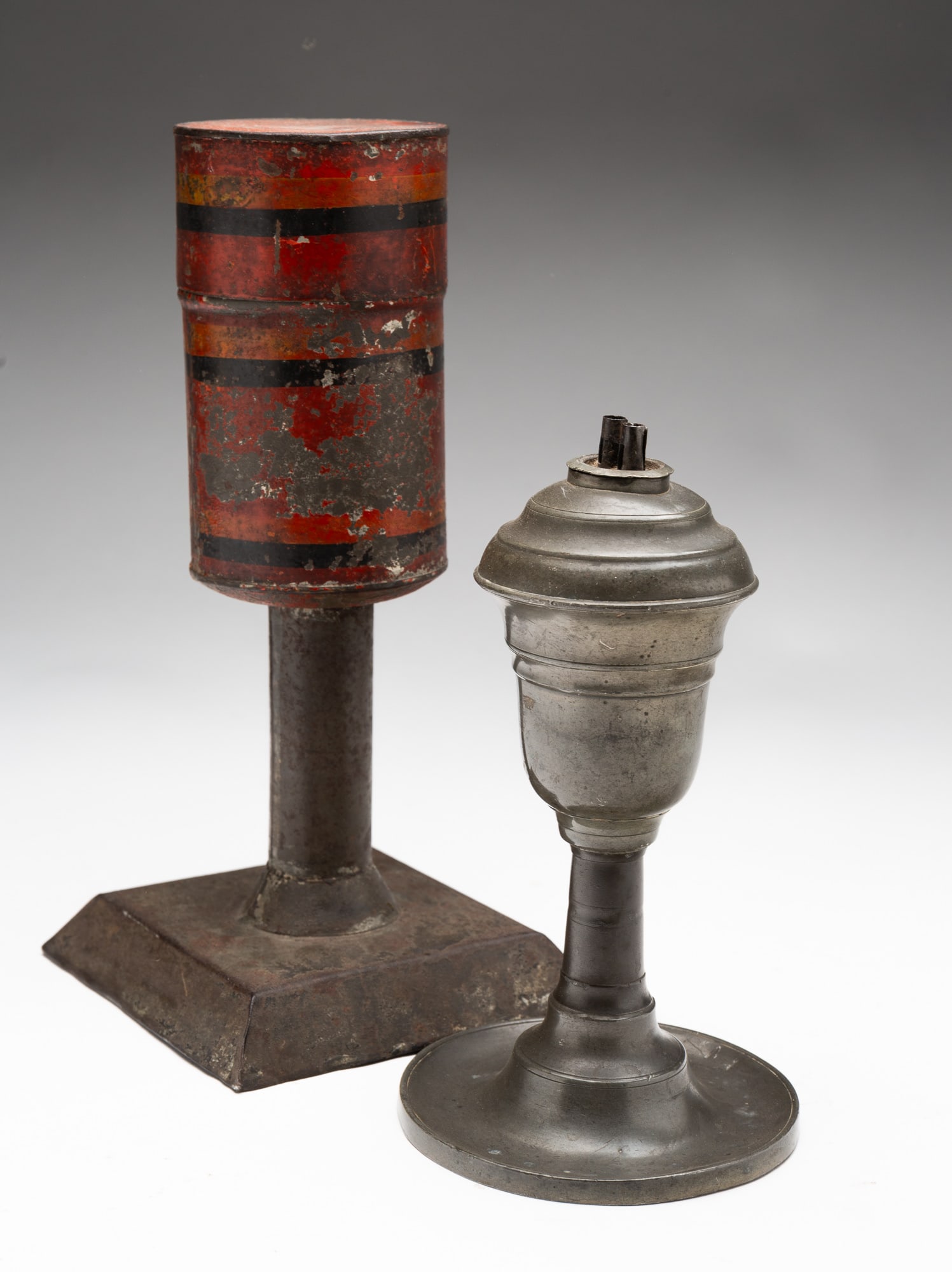 TWO WHALE OIL LAMPS.: American, 19th Century. A Morey And Ober Boston, Massachusetts pewter whale oil lamp. Double burner, inverted acorn font, column stem and saucer base, 8"h. A tole tinsmith made whale oil lamp, single