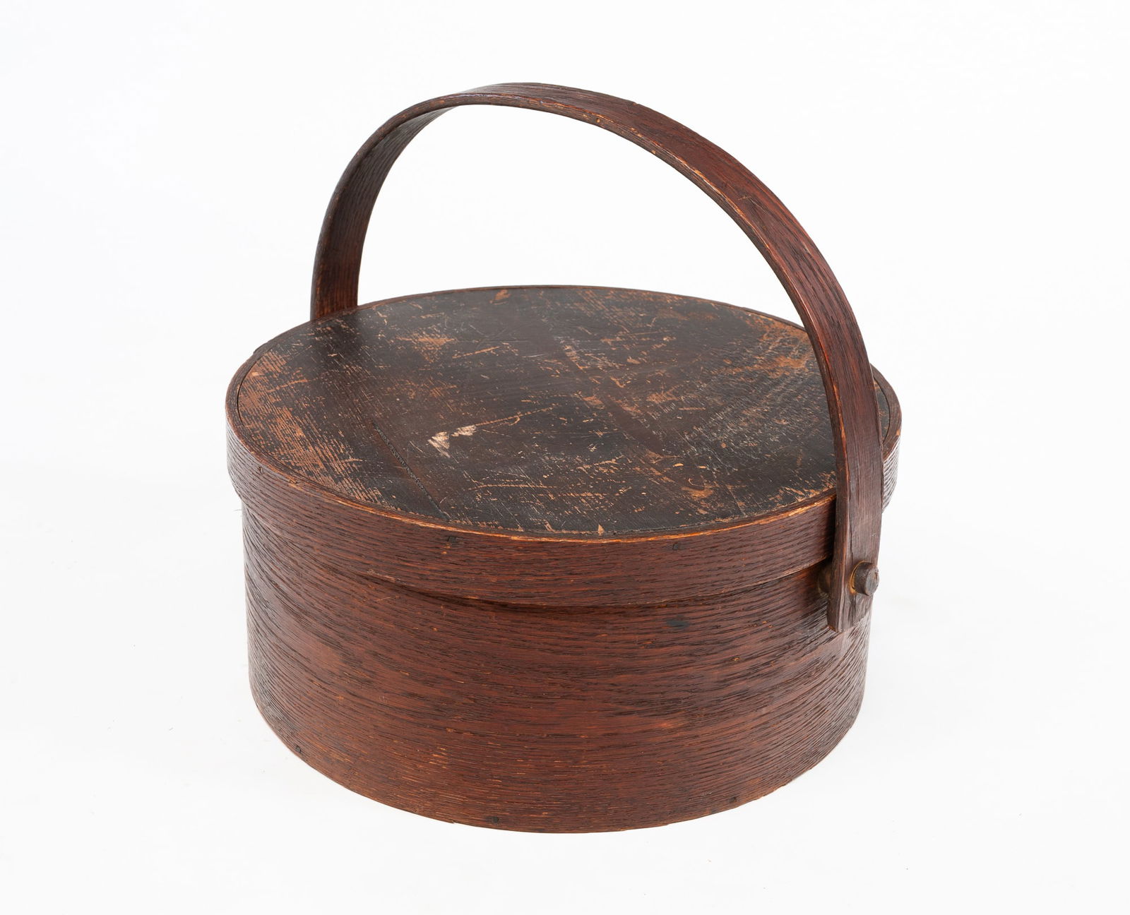 RED WASHED BENTWOOD CARRIER.: American, 19th Century. Of circular form and constructed with lapped joints having copper tacks, with a bentwood swing handle. With handle, 13.5"h 14.75"d. From the lifetime collection of James Michae