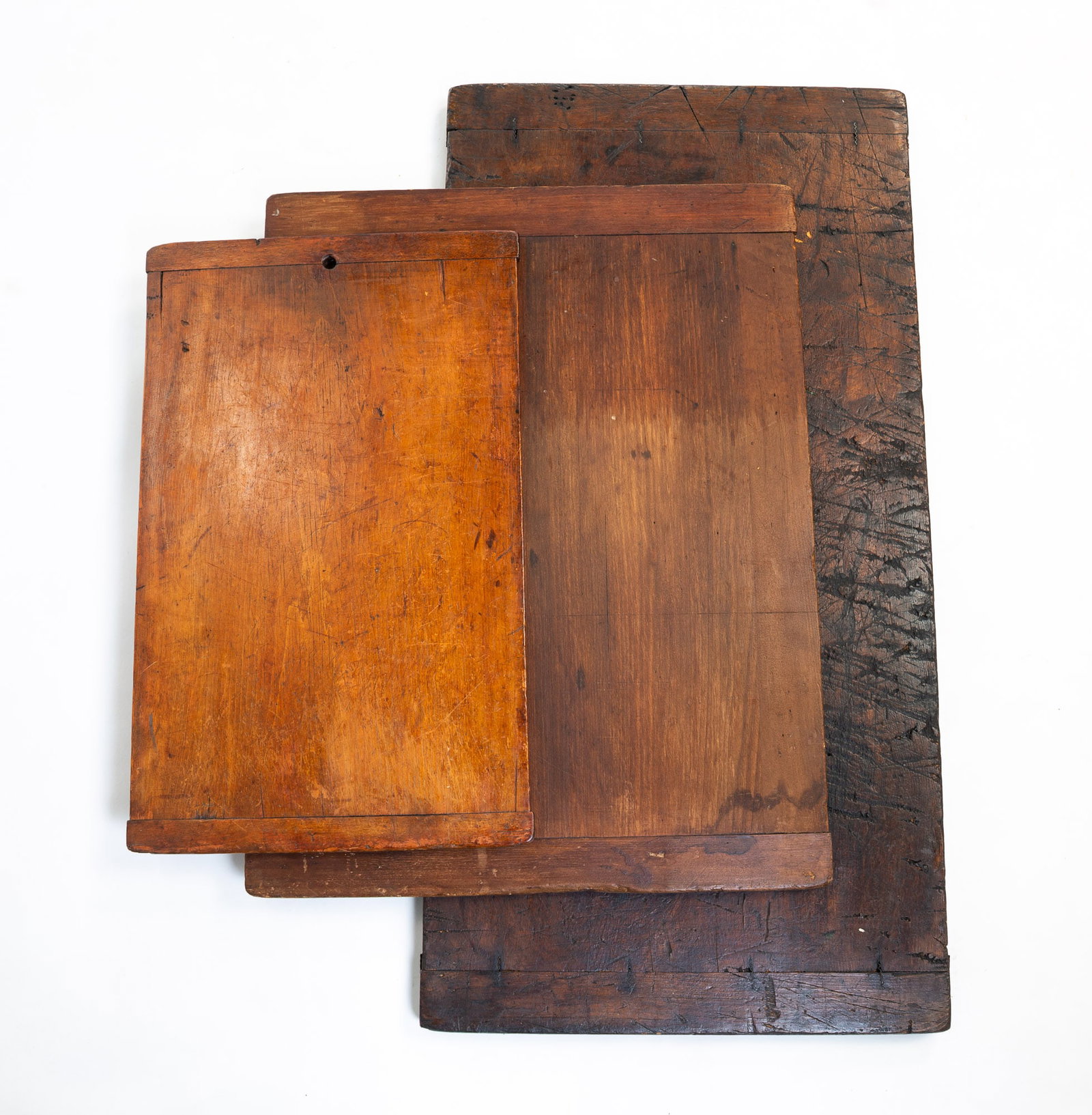THREE WOOD BREAD BOARDS.: American, 19th/20th Century. Pine. Of rectangular form. The largest having peg and metal construction, with both sides showing heavy use and wear. 1"h. 35.75"w. 18"d. The next largest having jointed e