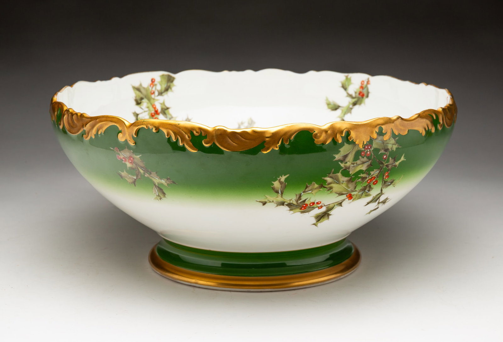 T&V LIMOGES "HOLLY" PUNCH BOWL.: France, 20th Century. Tressemanes & Vogt Limoges. With green and purple hallmarks. Green field with holly decoration and gold trim. 6.25"h. 14"d.
