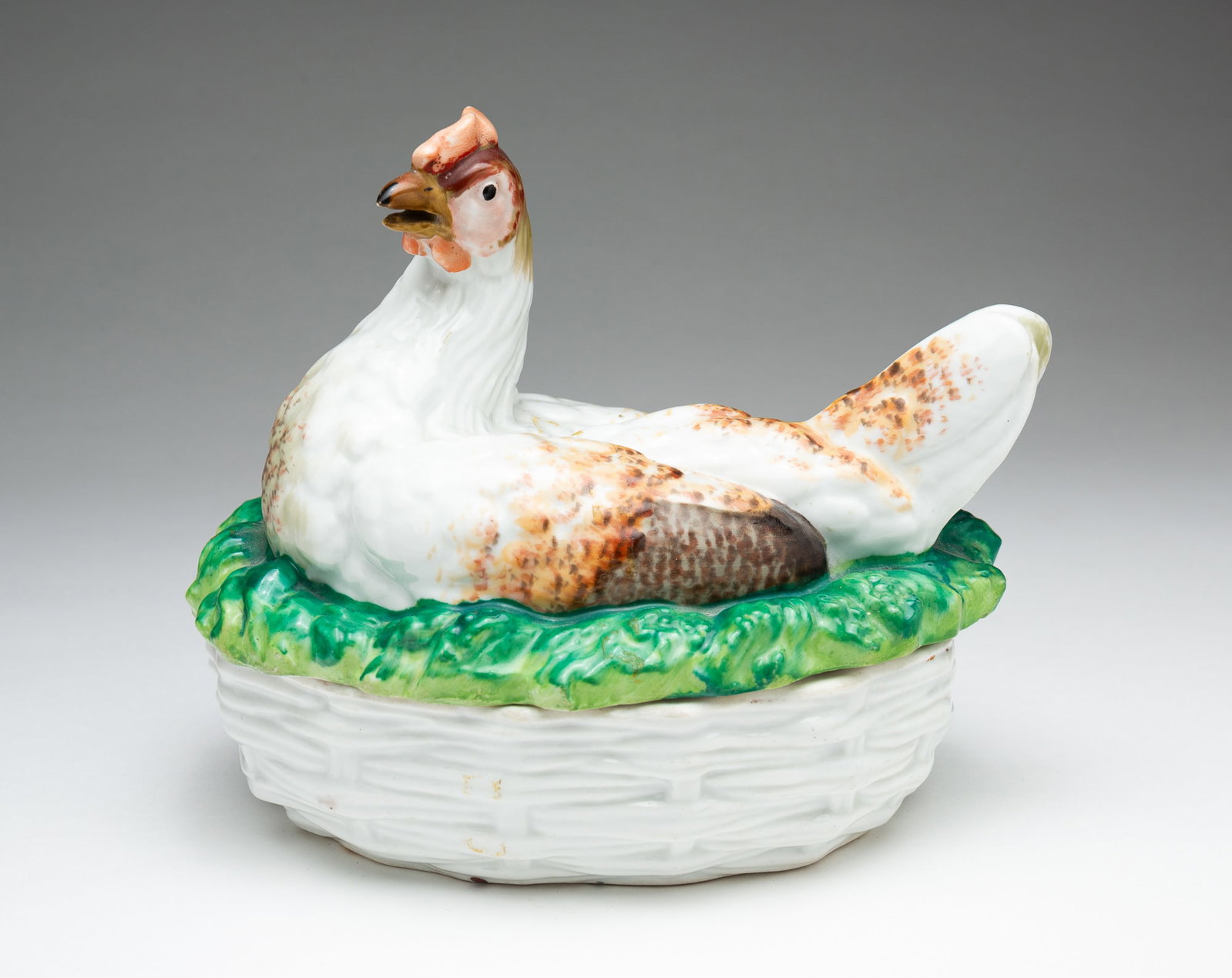 STAFFORDSHIRE HEN ON NEST.: England, 19th Century. High glaze. Hen with brown mottling on green grass, lid, and basket weave base. 6.75''h. 7''w.