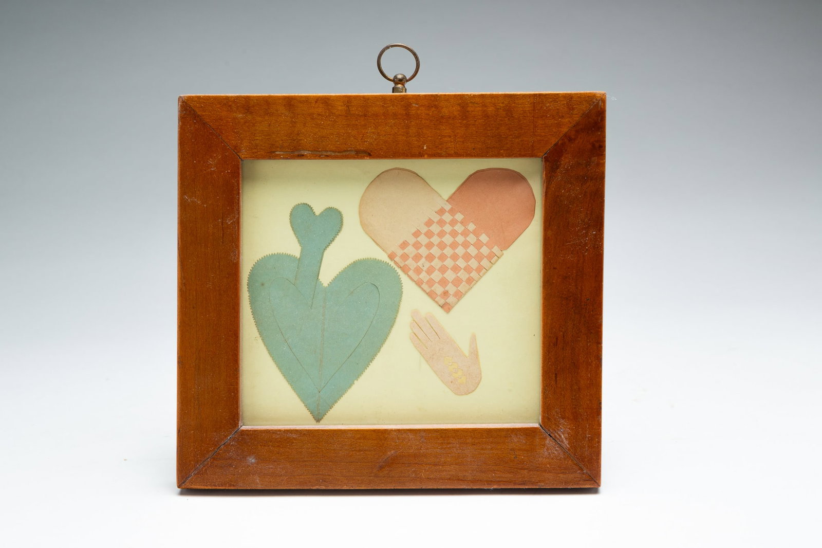 FRAMED VALENTINE.: American, 20th Century. Paper cut out in the Shaker manner in the shapes of two hearts and a hand, the larger heart with the paper woven together, the other heart and hand with delicately cut designs,