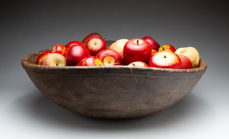 LARGE TURNED WOOD BOWL FILLED WITH APPLES.