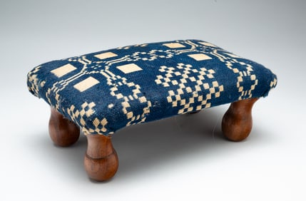 DIMINUTIVE UPHOLSTERED STOOL.