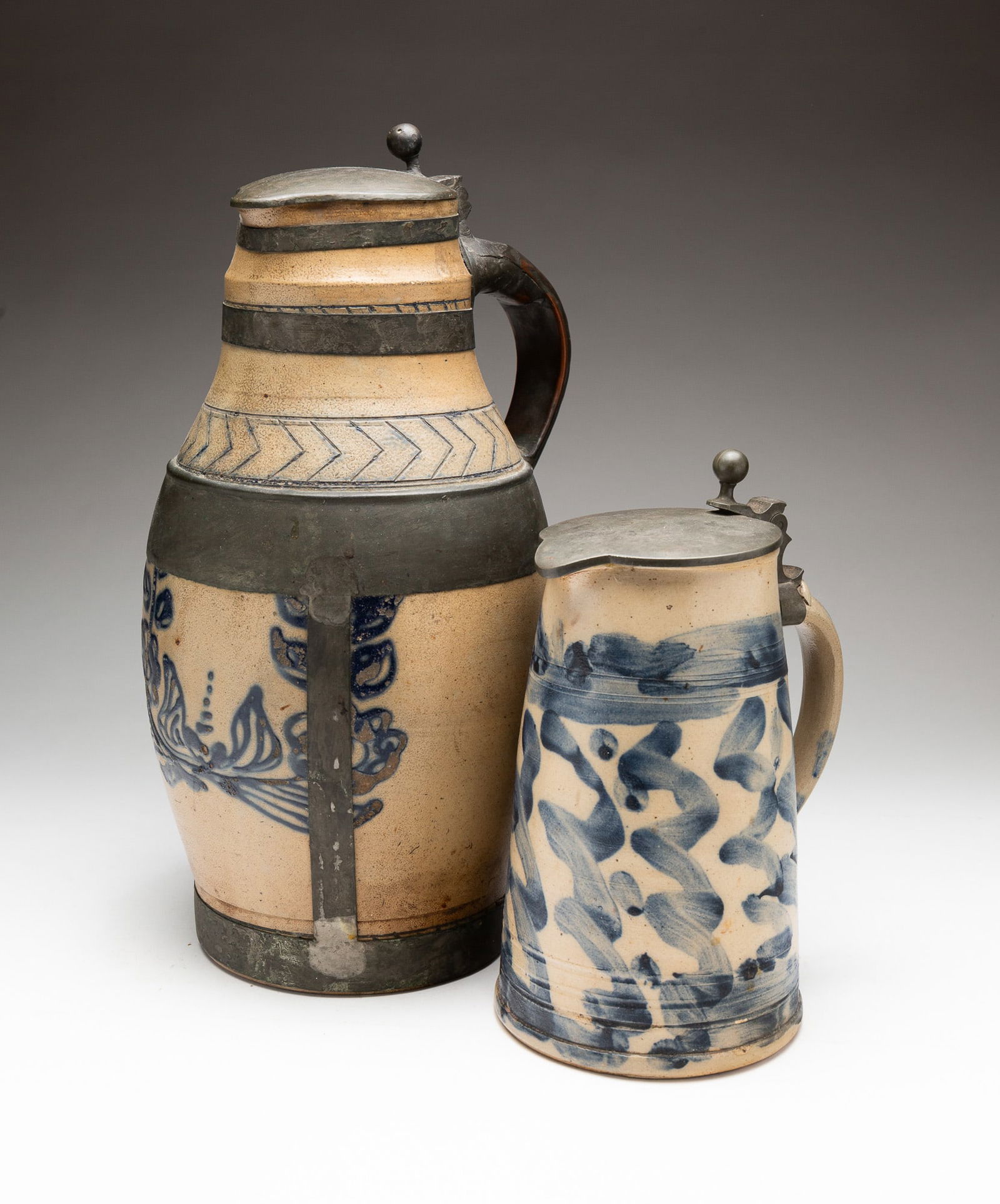 TWO STONEWARE TANKARDS, ONE WITH A MAKE DO REPAIR. (1 of 4)