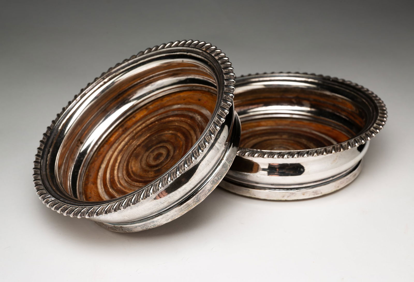 PAIR OF ENGLISH REGENCY SHEFFIELD SILVER PLATE CHAMPAGNE OR WINE COASTERS BY MATTHEW BOULTON (1728-1: England (Birmingham), 18th Century. Hallmarks with maker's old Sheffield plate twin sun mark. Gadrooned rims with turned wood mahogany bottoms. 1.75"h. 6"d.
