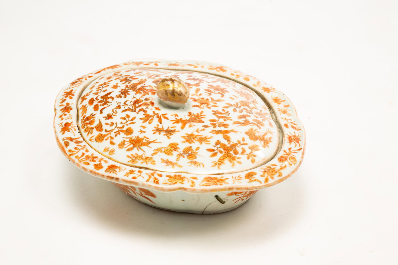 EXPORT COVERED VEGETABLE, SACRED BIRD AND BUTTERFLY.: China, 19th Century. Shaped oval covered vegetable with orange and gold decoration. Staple repair to bottom. 4"h. 11"w. From the collection of Mark and Sandy Keily.
