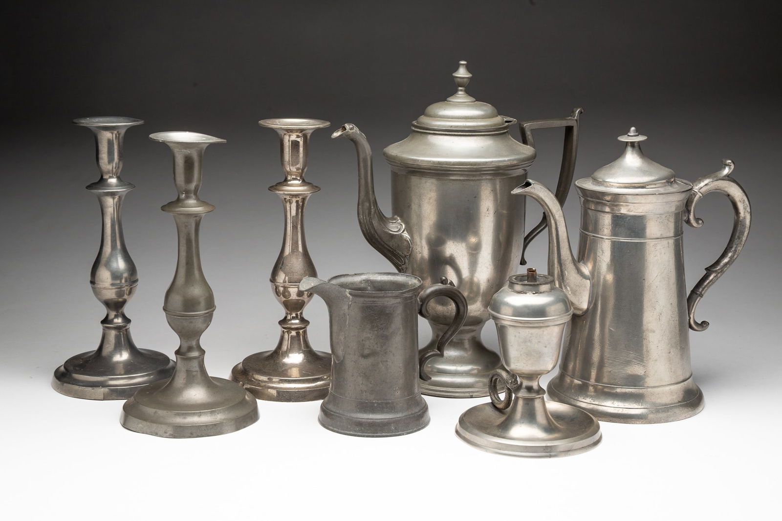SEVEN CINCINNATI PEWTER ITEMS, INCL. HOMAN & CO. AND SELLEW & CO.: American (Cincinnati, Ohio), 19th Century. Lighthouse tall pot with gooseneck spout and scrolled handle, unmarked Sellew, 10"h. Homan footed tall pot, 12"h. A pair of baluster stem candlesticks, unmar