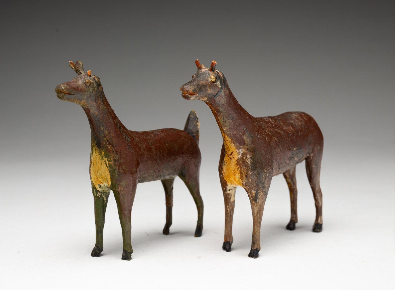TWO AMERICAN FOLK ART CARVED AND PAINTED WOOD DEER.: American, 19th Century. Two free-standing carved and painted wooden deer, 4"h. 4.5"l.