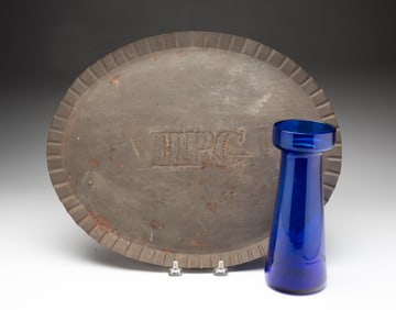 A BLOWN GLASS CROCUS VASE AND A TIN TRAY.