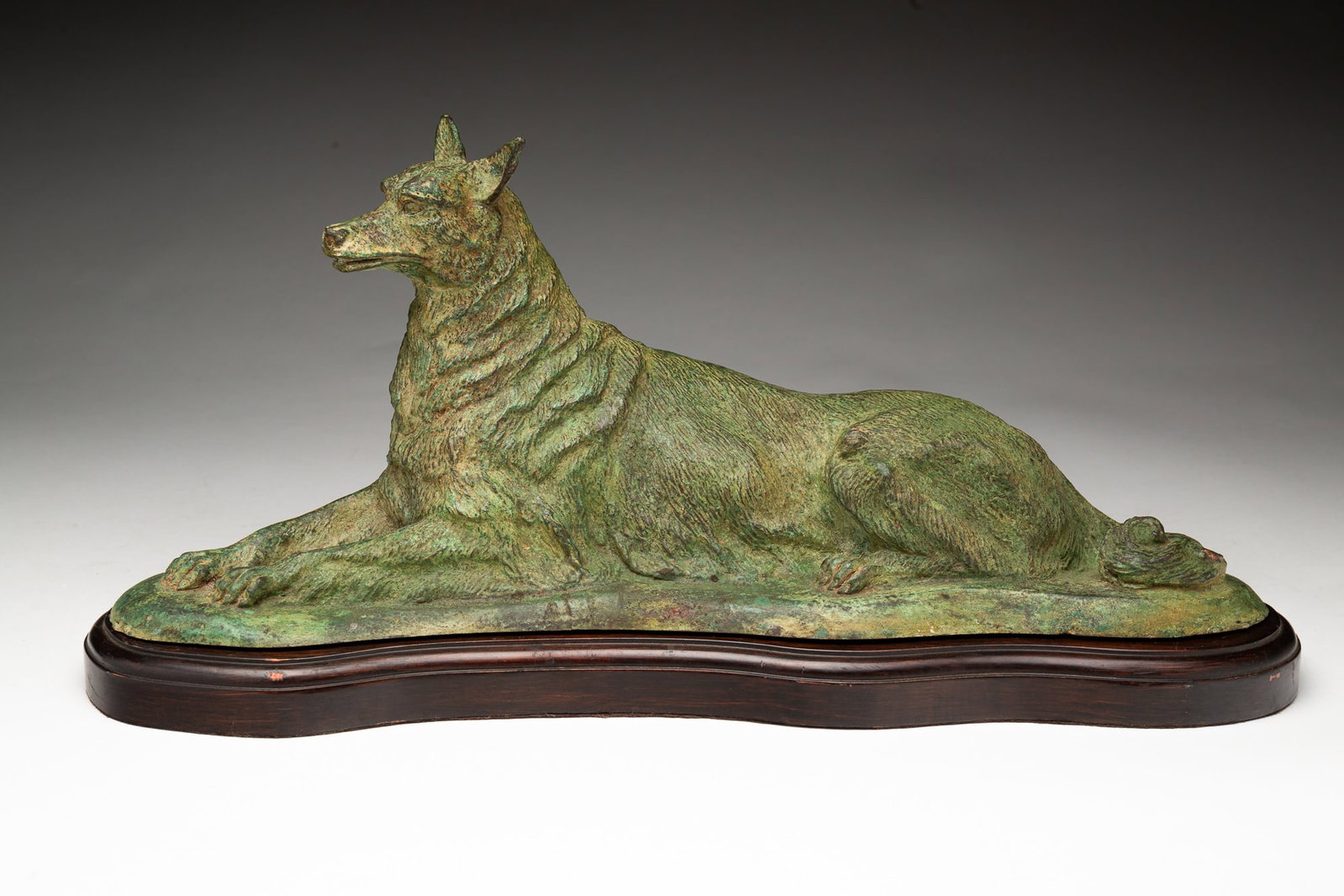 MANNER OF ALBERT LAPLANCHE (FRENCH, 1854-1935) RECUMBENT GERMAN SHEPARD PATINATED AND CAST BRONZE: Manner of Albert LaPlanche (French, 1854-1935), 20th Century. Verdigris-patinated and cast bronze German Shepard in a recumbent pose. Presented on a wooden base. 8"h. 17"w.