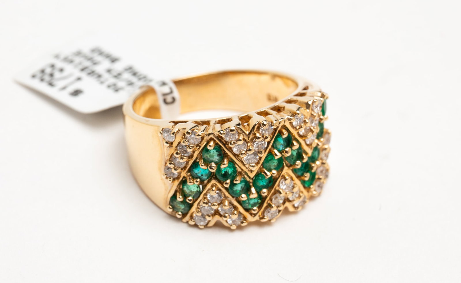 YELLOW GOLD BAND PAVE SET WITH DIAMONDS AND EMERALDS.: Contemporary. 14K gold wide band pave set with round brilliant diamonds and round emeralds. Total weight of diamonds and emeralds 1.30cts. Band measures approx. 11.2mm at the front, size 6.75, 7.1gr.
