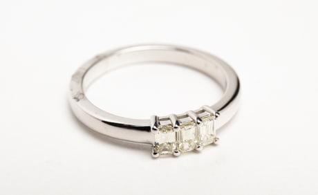 THREE - STONE EMERALD CUT DIAMOND RING.