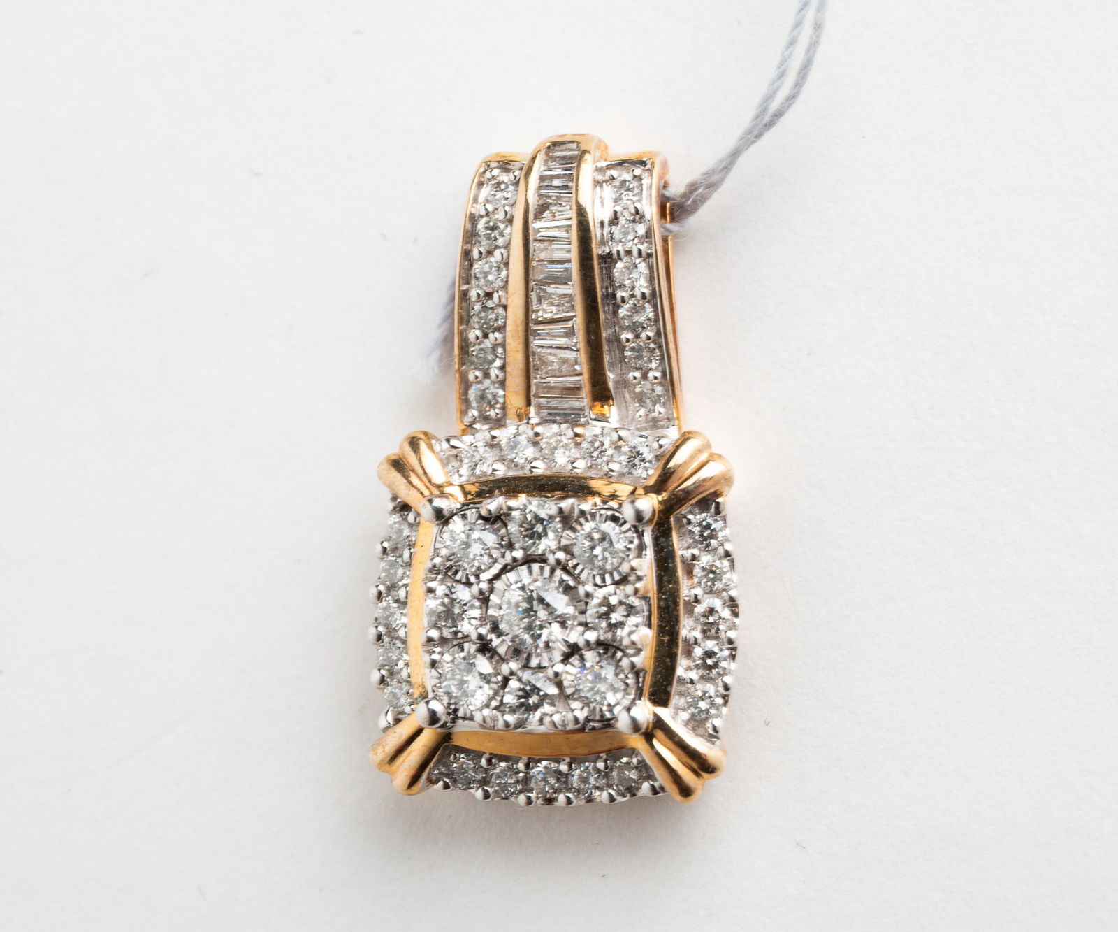 MIXED CUT DIAMOND ILLUSION CLUSTER PENDANT.: Contemporary. 10 karat yellow gold pendant, double square design with round brilliant diamonds, bail with round brilliant diamonds and channel set baguettes. Measures approx. 1"l, 4.0gr., total diamon