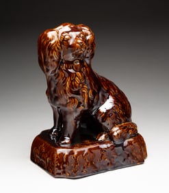 AMERICAN YELLOWWARE SEATED SPANIEL WITH ROCKINGHAM GLAZE.