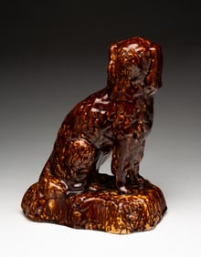AMERICAN YELLOWWARE SEATED SPANIEL WITH ROCKINGHAM GLAZE.
