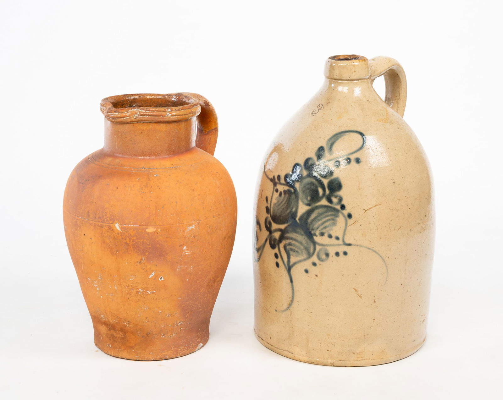 REDWARE PITCHER AND THREE GALLON STONEWARE JUG.: American, 19th Century. A redware pitcher with incised banded rim and applied strap handle, 13"h. And an impressed "3" gallon jug with cobalt freehand decoration and applied strap handle, 15.5"h.