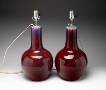 PAIR OF CHINESE SANG DE BOEUF GLAZED PORCELAIN VASE LAMPS.: China, 19th Century. Bottle form vases having long necks ending in bulbous bodies, glazed in red with streaks of purple and blue, unmarked, electrified. Each, 19.5"h.