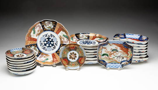 GROUP OF TWENTY-FOUR JAPANESE IMARI PORCELAIN PLATES.: Japan, 19th Century. Eight rectangular plates with lobed corners; the centers decorated with polychrome and gilt cranes, trees, and clouds; the sides with foliate forms, good luck symbols, and diaper