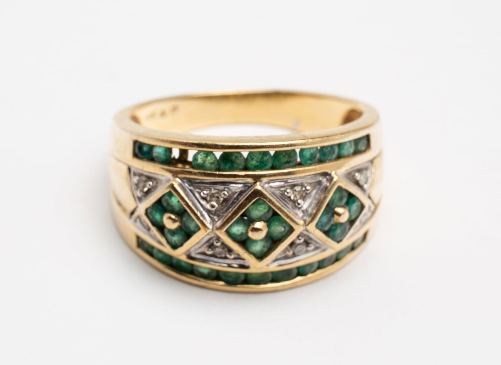TWO-TONE 14 KARAT BAND WITH EMERALDS AND DIAMONDS.: Contemporary. Yellow gold wide band with border of channel set round emeralds, embellished with center design of round emeralds and single cut diamonds. Diamonds set in white gold. Band measures appro