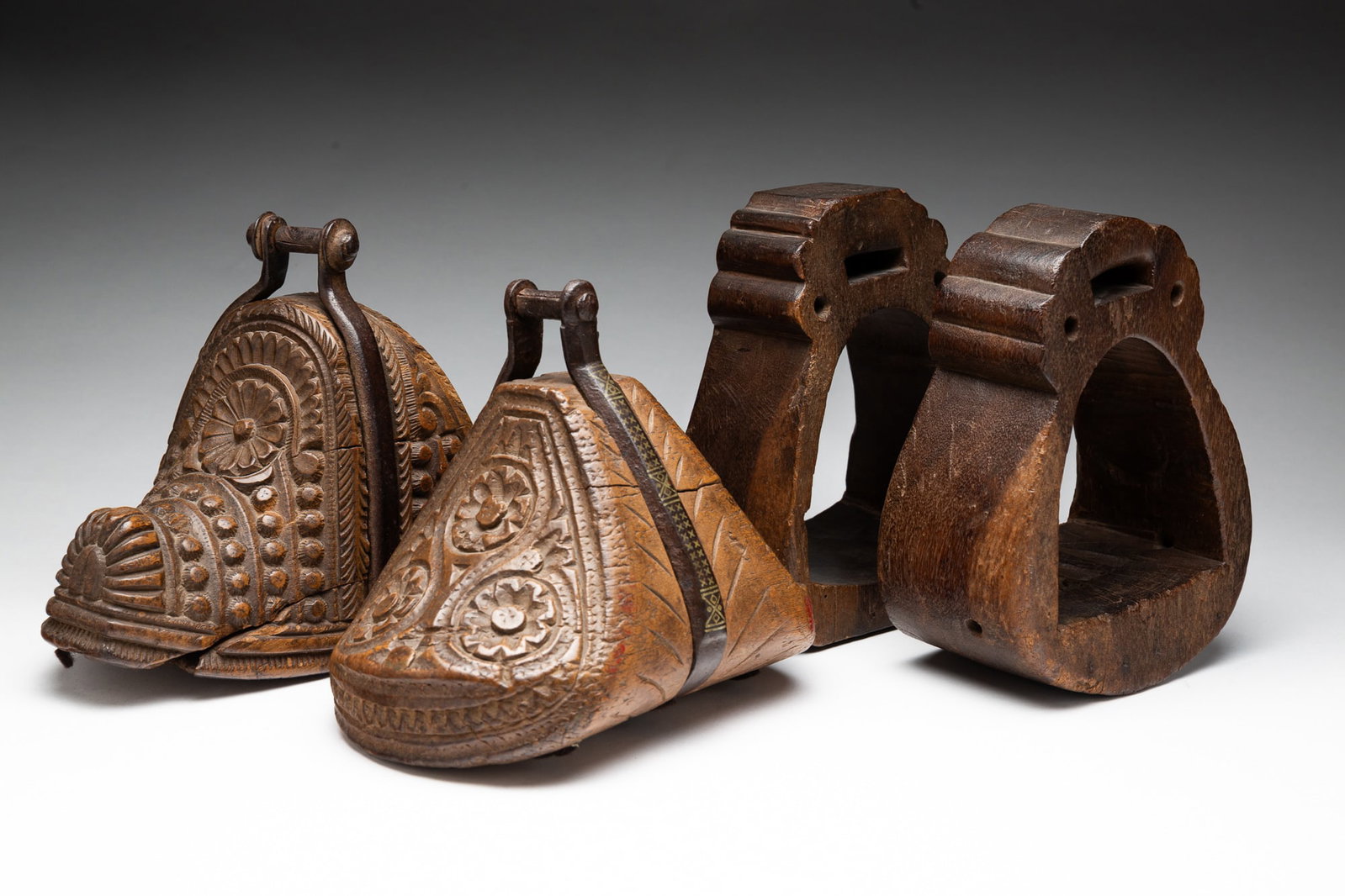 FOUR SOUTH AMERICAN WOODEN RIDING STIRRUPS.: South America, 19th Century. Comprising two foliate carved stirrup with iron hardware and two carved stirrups. Tallest, 8"h.