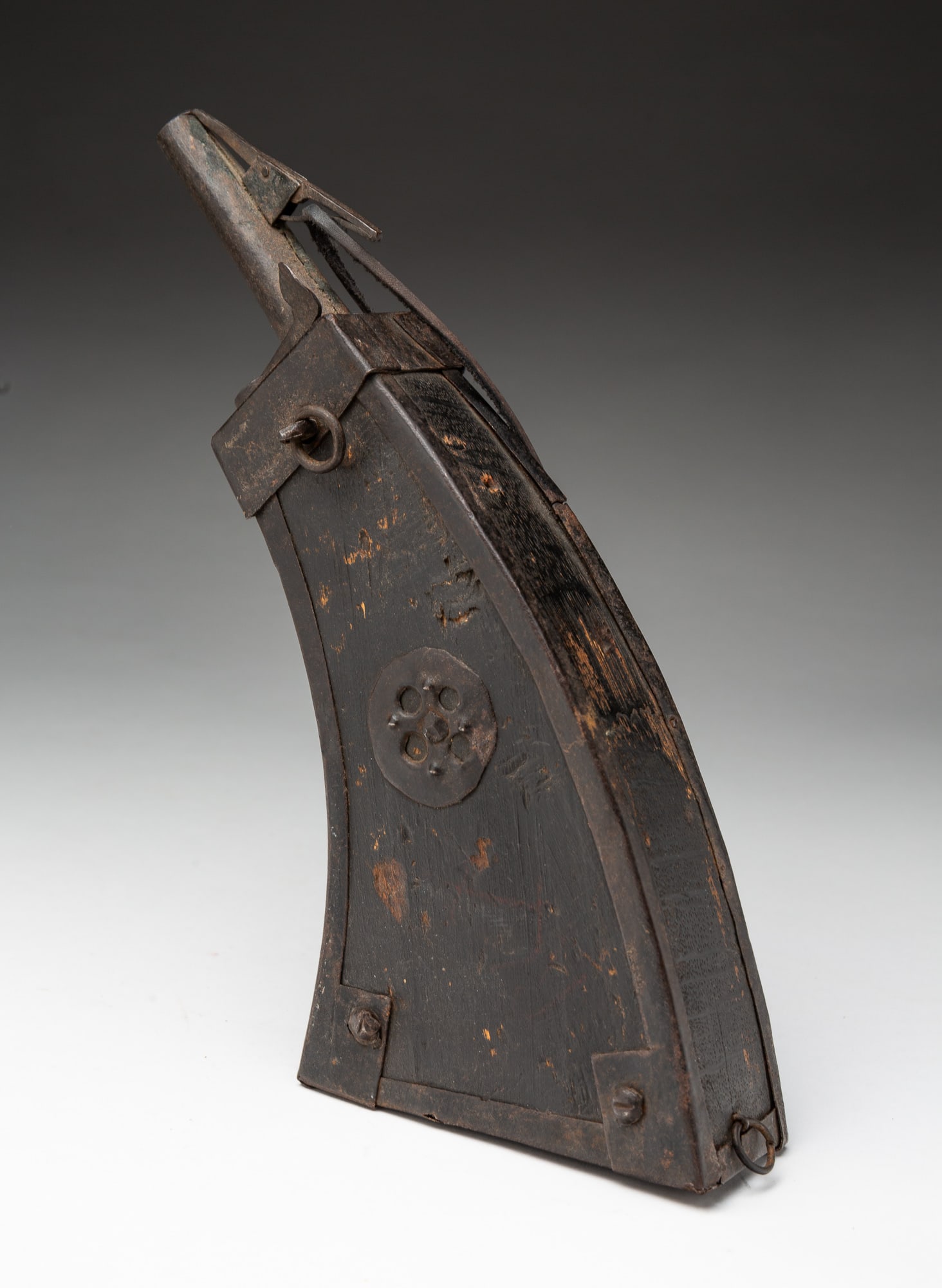 GERMAN MUSKETEER POWDER FLASK.: Germany, ca. 1600. Flat wood body of curving trapezoidal form with iron mountings, a spout with a spring cover, a belt hook, and a leather strap. 12.5"h.