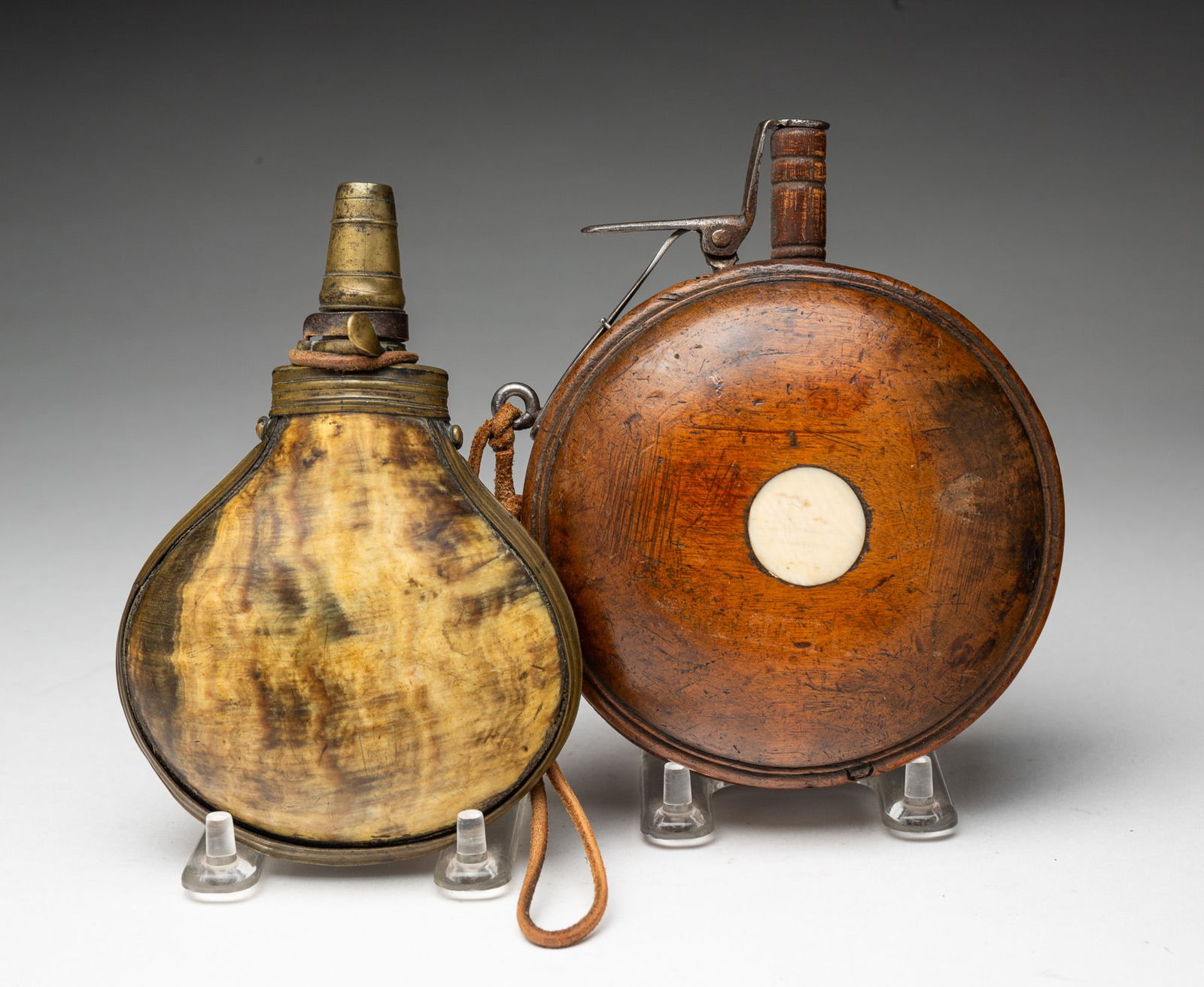 RUSSIAN WOODEN POWDER FLASK AND EUROPEAN LANTHORN HORN POWDER FLASK.: Nineteenth-century Russian powder flask of circular form with carved rings on one side and an inlaid circular bone on the other, with iron mountings and a leather strap. 5.75"h. 4.75"w. 18th-century E