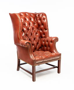 CHIPPENDALE STYLE BUTTONED-DOWN LEATHER WINGBACK ARMCHAIR WITH BRASS TACKS.: 20th Century. Oxblood red leather. Button-tufted, small rolled arms with brass tack trim. Straight legs with box stretchers. 16" seat. 45"h.