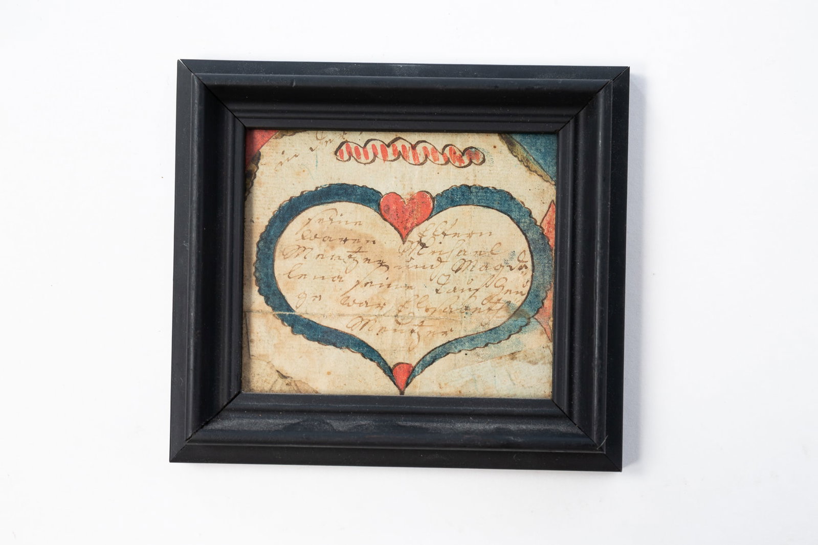 PENNSYLVANIA WATERCOLOR BOOKPLATE FRAKTUR WITH HEART.: American (Pennsylvania), Late 18th Century. Central heart in blue and red filled with writing, in an ebonized frame behind glass, 4.75"h. 5.25"w.Provenance: From the Lifetime Collection of the late Gi