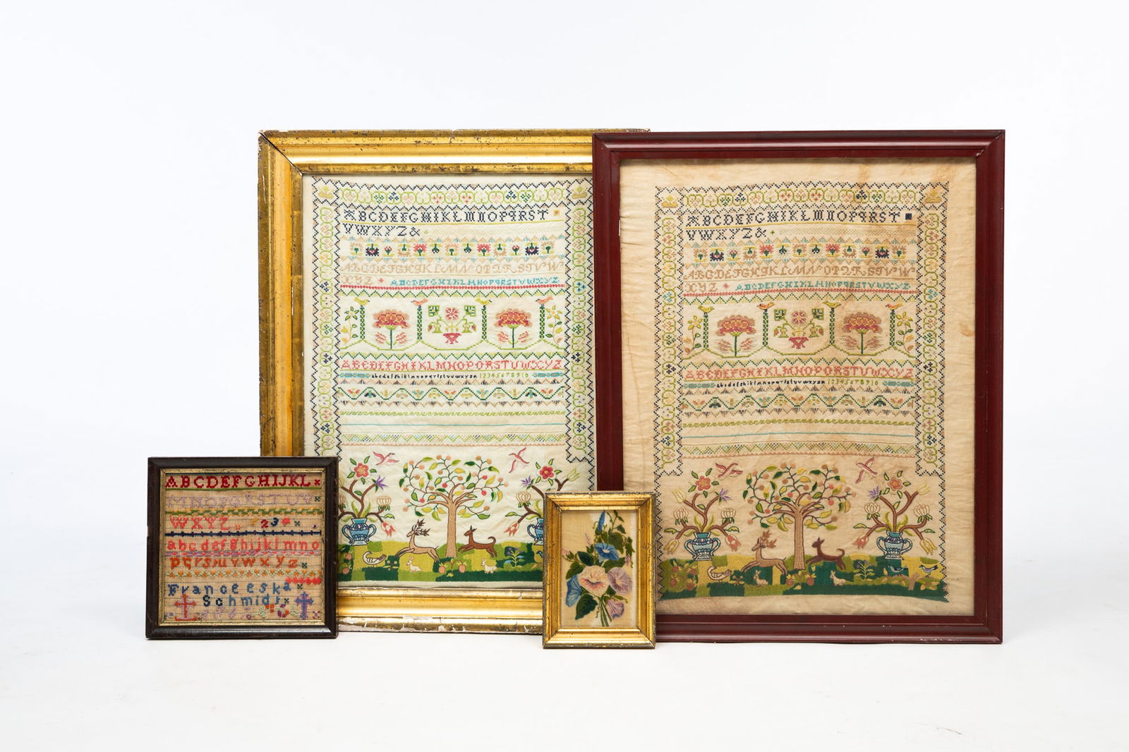 FOUR AMERICAN TEXTILE WORKS, INCLUDING SAMPLERS AND A THEOREM.: American, 19th-20th Century. A diminutive theorem on velvet of flowers in a gilt frame behind glass, 8.25"h. 6"w. A needlepoint sampler by Franceeska Schmidt, colorful yarn on linen, two alphabets, cr
