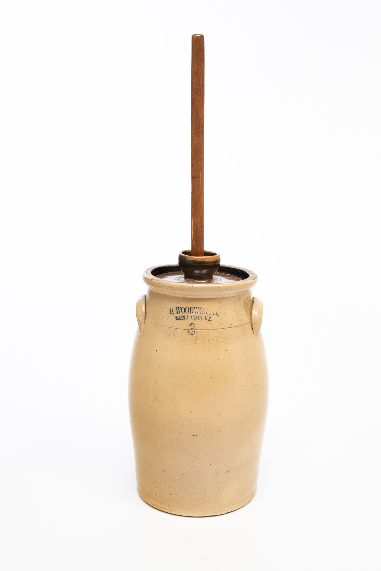 F. WOODWORTH (BURLINGTON, VERMONT) STONEWARE THREE-GALLON BUTTER CHURN.: American (Burlington, Vermont), 19th Century. Three gallon butter churn in typical cylindrical form, with lid and dasher. Stamped "F. WOODWORTH BURLINGTON, VT." near lip. 15.25"h.Provenance: From the