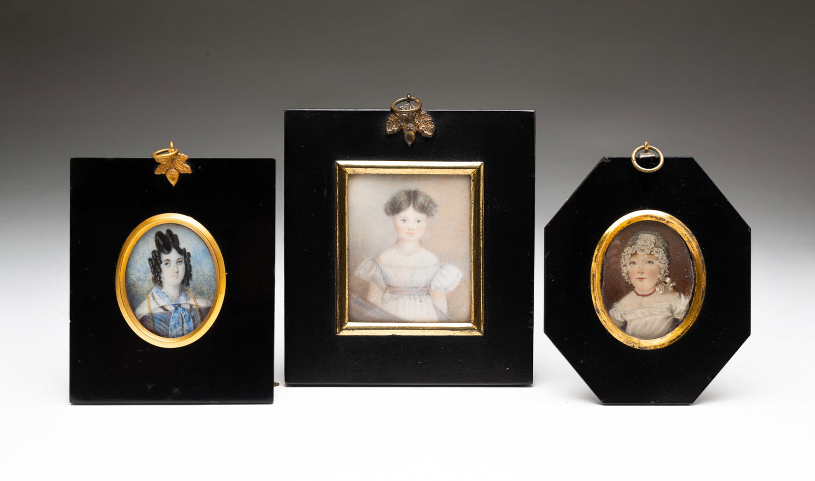 THREE ENGLISH SCHOOL MINIATURE GOUACHE PORTRAITS OF GIRLS.: England, 18th and 19th Centuries. Gouache on wafers of natural material. The first with hair parted in the middle and wearing a white dress, illegible inscription on verso; the second wearing a white 