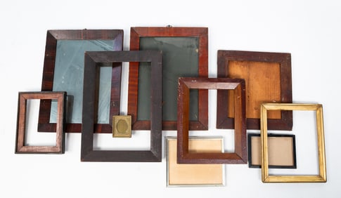 A FRAMED MIRROR AND A GROUP OF WOODEN FRAMES.