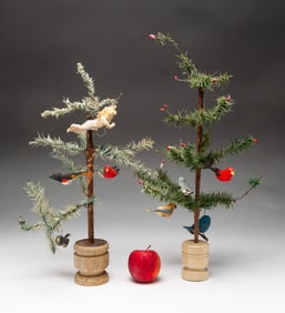 TWO MINIATURE FEATHER CHRISTMAS TREES WITH CARVED AND PAINT-DECORATED BIRDS.