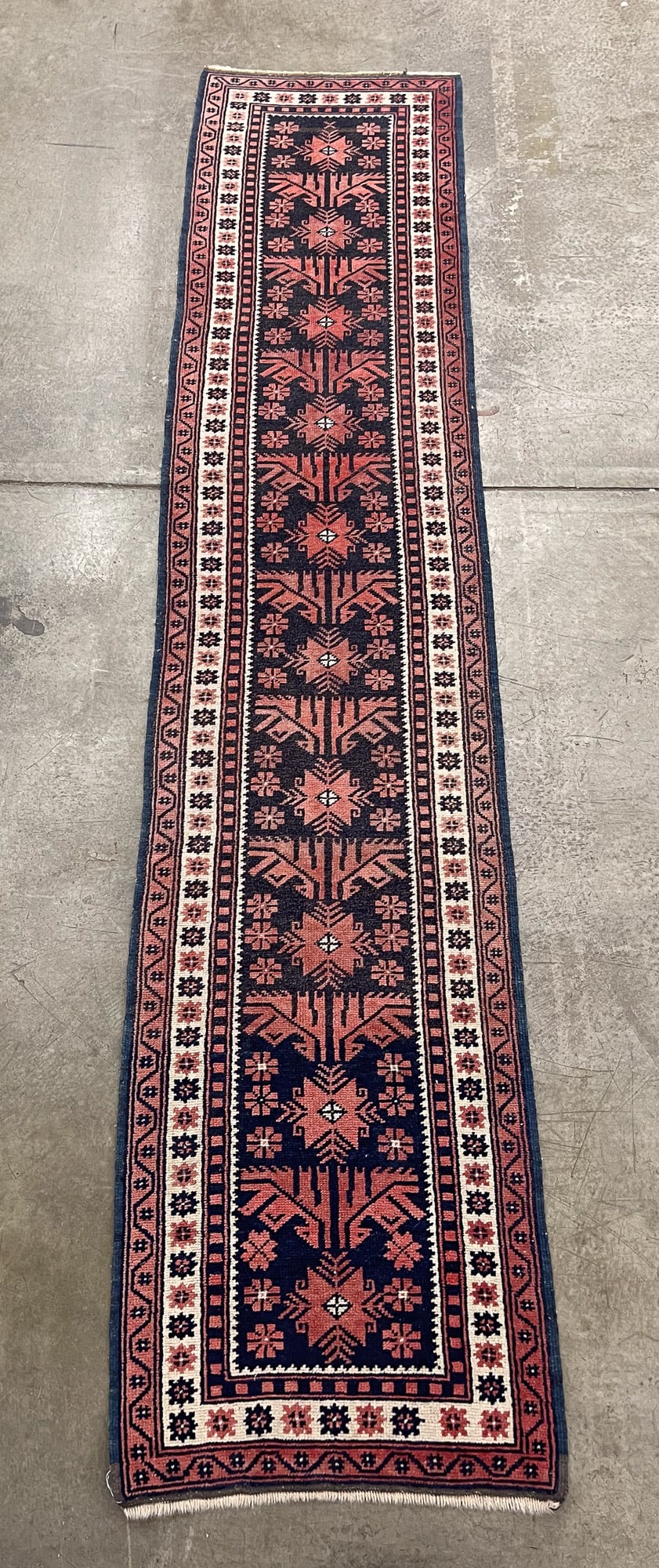 YAGCI BEDIR RUNNER.: Yagci Bedir. Dark blue field, cream and rust border, and overall geometric and floral pattern in rust green and blue. 2'w. 9'6"l. Provenance: From The Lifetime Collection of Janet & Charles Muto (Otta
