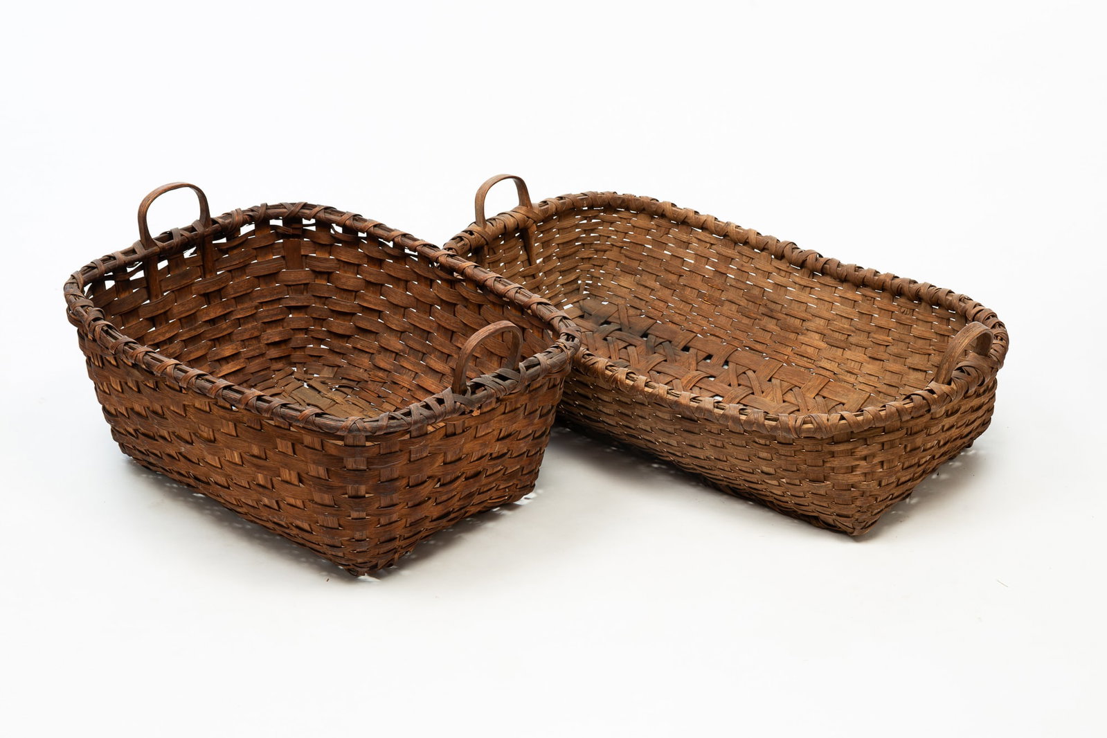 TWO LARGE WOVEN SPLINT HANDLED BASKETS.: American, 19th Century. Rectangular woven split baskets with bentwood handles. 14"h. 26.5"w. 20.5"d. and 11"h. 33.5"w. 21.5"d.