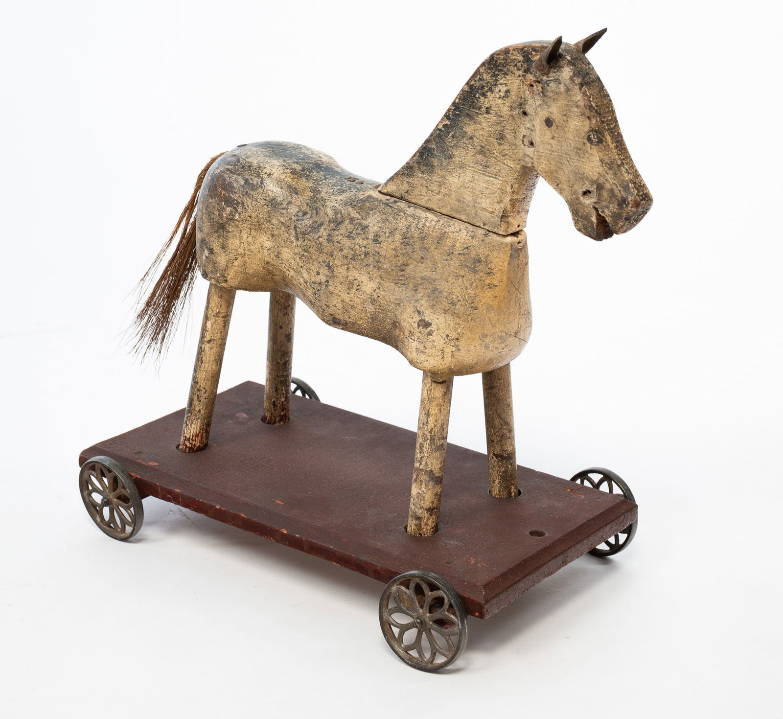 EARLY AMERICAN HORSE PULL TOY.: American, Early 20th Century. Wooden horse with black paint, leather ears, on a painted base with metal wheels. 15"h. 8.5"w. 14"l.